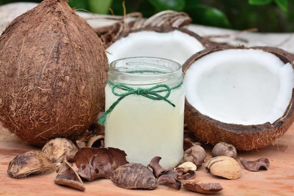 Noix de coco et pot d'huile de coco, suggérant ses bienfaits pour un cuir chevelu irrité.