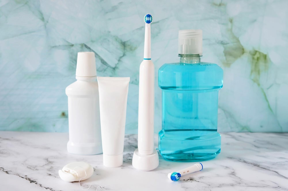 Assortiment de Produits d'Hygiène Dentaire, incluant une brosse à dents électrique, du dentifrice et un bain de bouche.