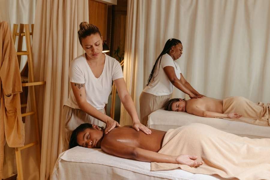Deux personnes profitent d'un premier massage en couple dans un salon de bien-être lumineux.