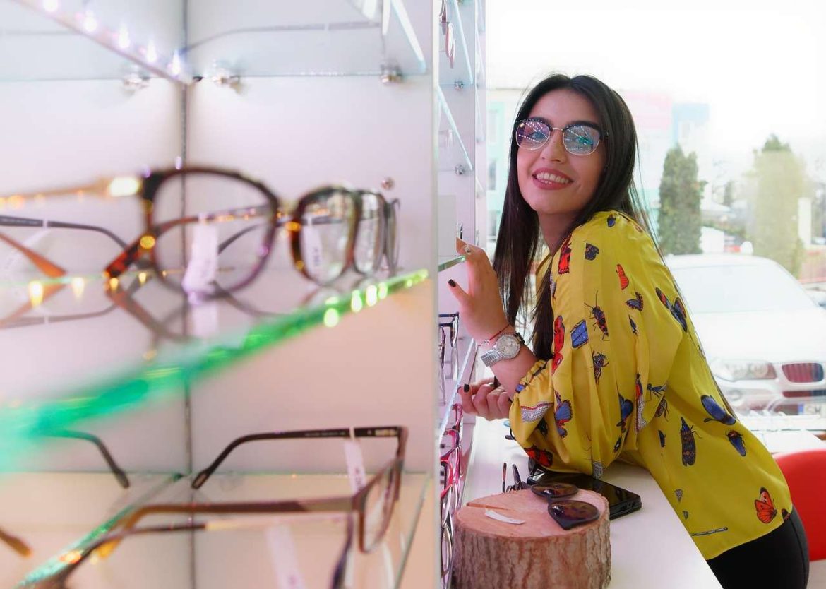 Une cliente souriante essayant des lunettes dans un magasin, illustrant comment trouver un opticien fiable à Tarbes.